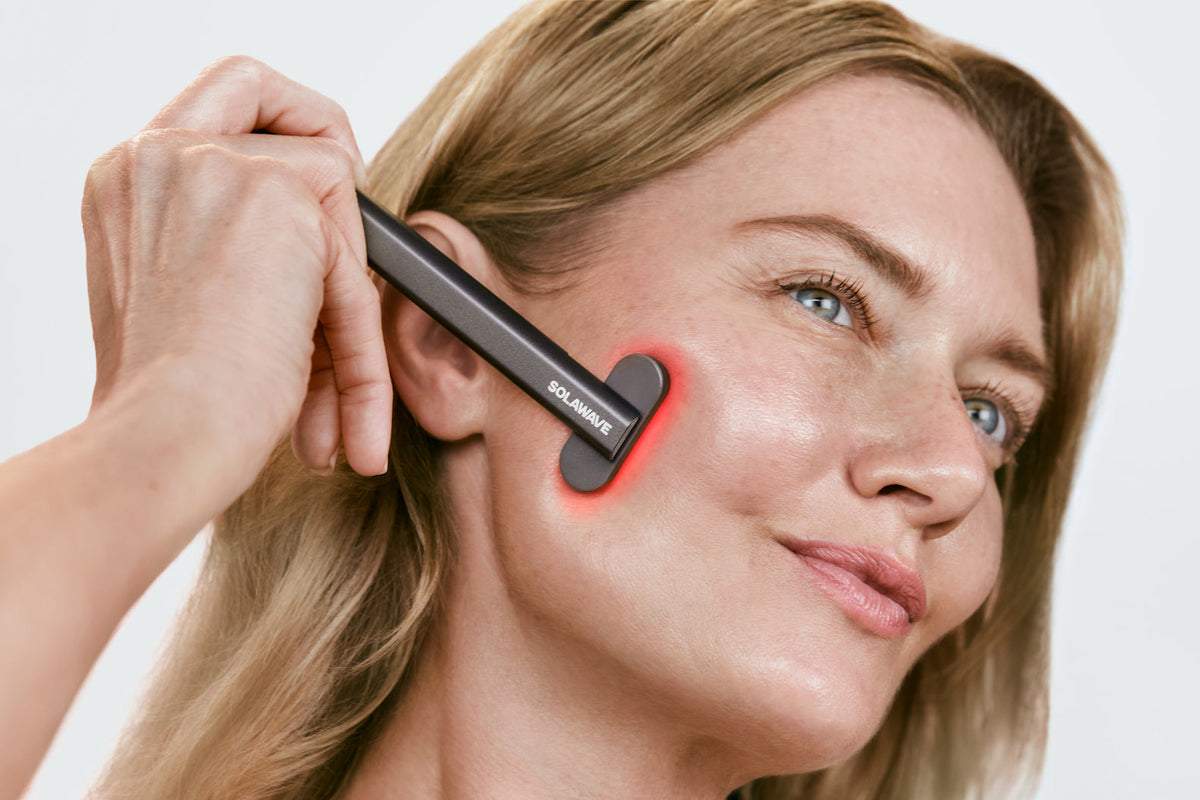Solawave - an image of a woman using a red ligh therapy device on her face