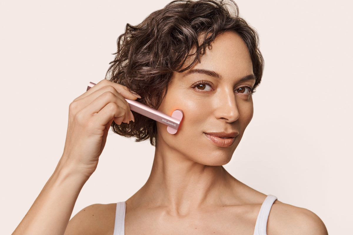 An image of a woman using a red light therapy device on her face to combat wrinkles