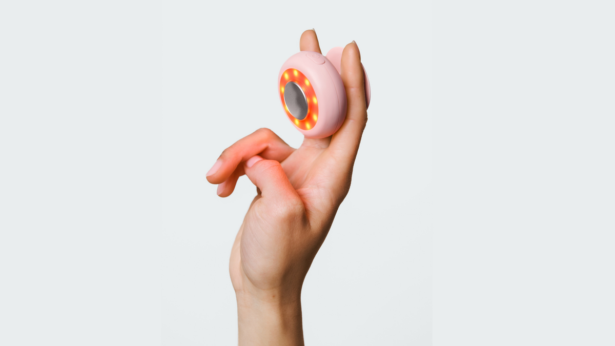 An image of a hand holding up a red light therapy device 