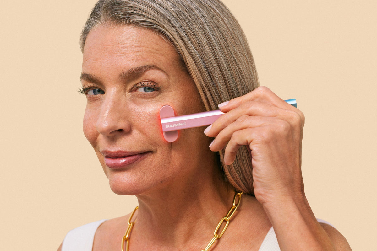 An image of a woman using red light therapy on her face