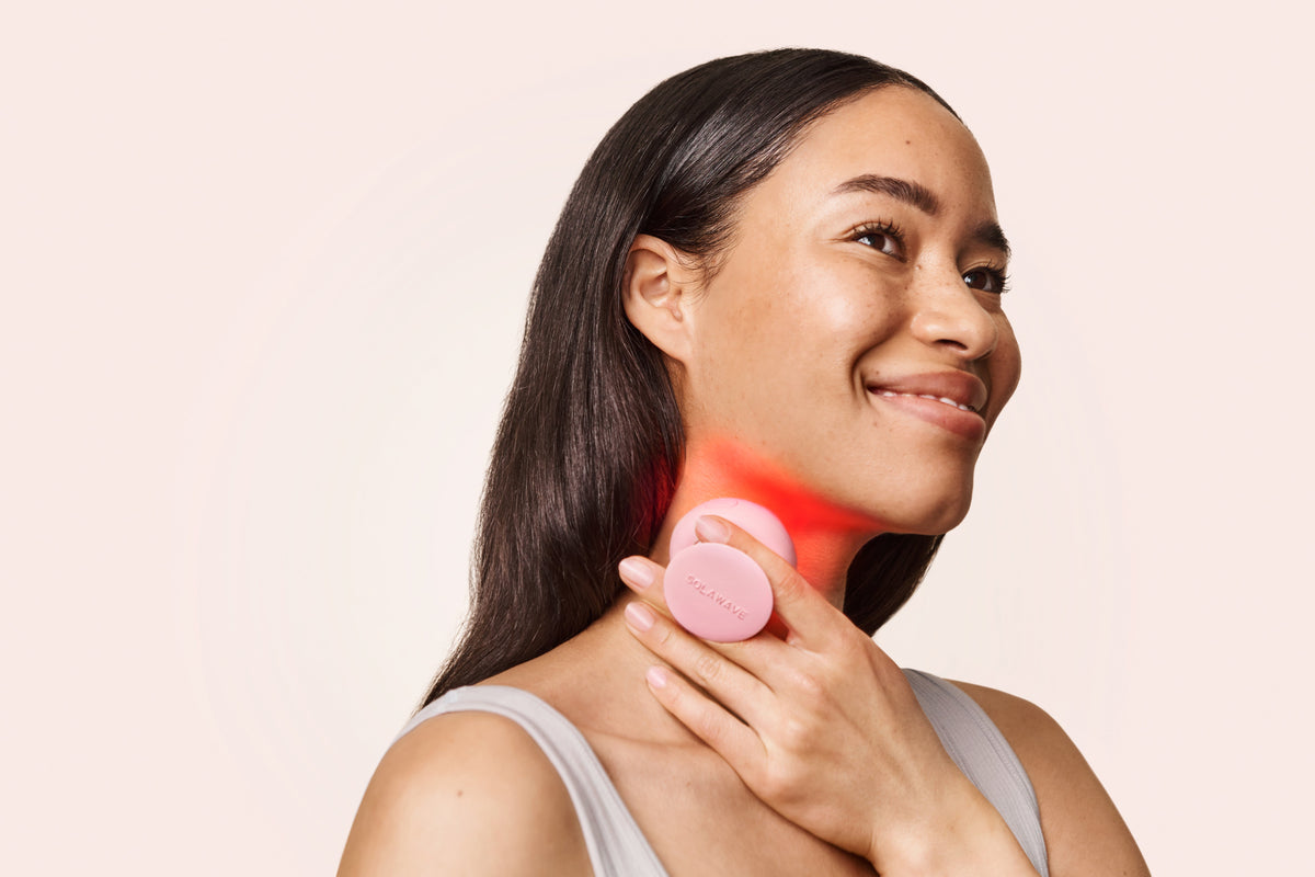 An image of a woman using red light therapy on her neck