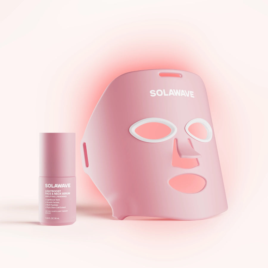 The Wrinkle Retreat Face Mask & LightBoost Serum Kit by Solawave features a rose LED mask, designed with eye, nose, and mouth cutouts for red light therapy. Paired with the pink tube of serum featuring white text, its perfect for targeting fine lines and wrinkles in a softly lit setting. || Rose