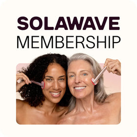 Two women smile while using skincare tools on their cheeks, promoting Inveterates Solawave Membership, which offers the convenience of canceling anytime. The backdrop is a calming light beige.